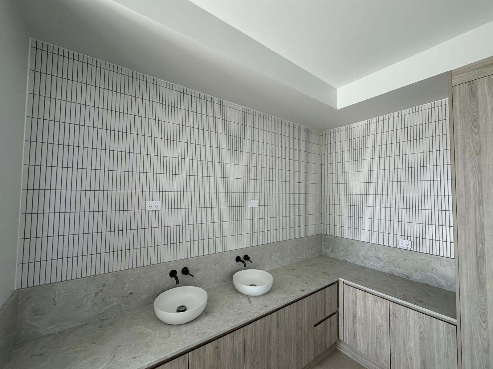 Double basin vanity with white vertical finger tiles on the walls