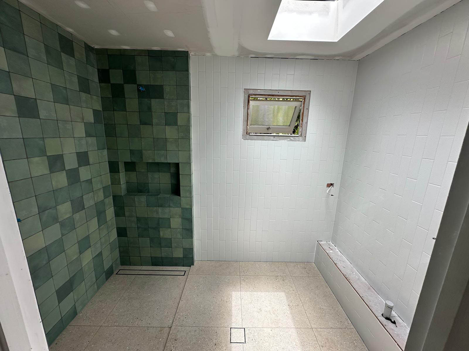 Bathroom with green square feature tiles, white wall tiles and a speckled floor