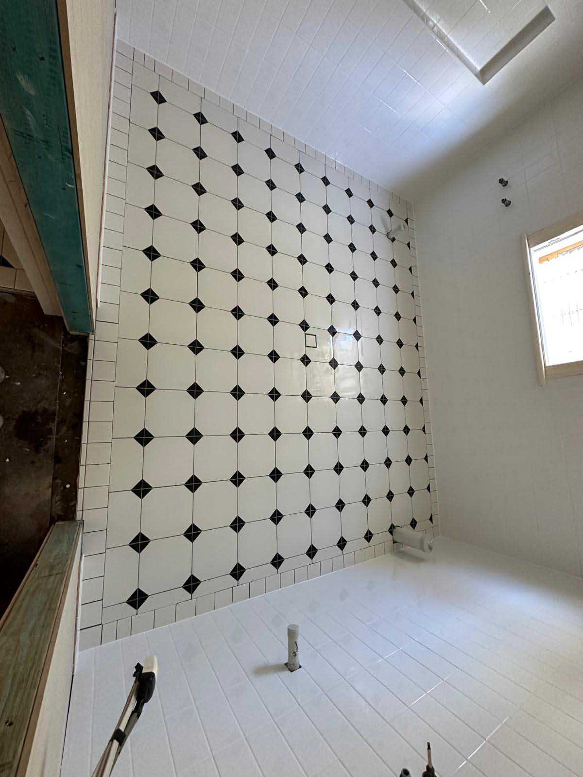 Bathroom wall in white octagon tiles with black dot inserts, before fit-out
