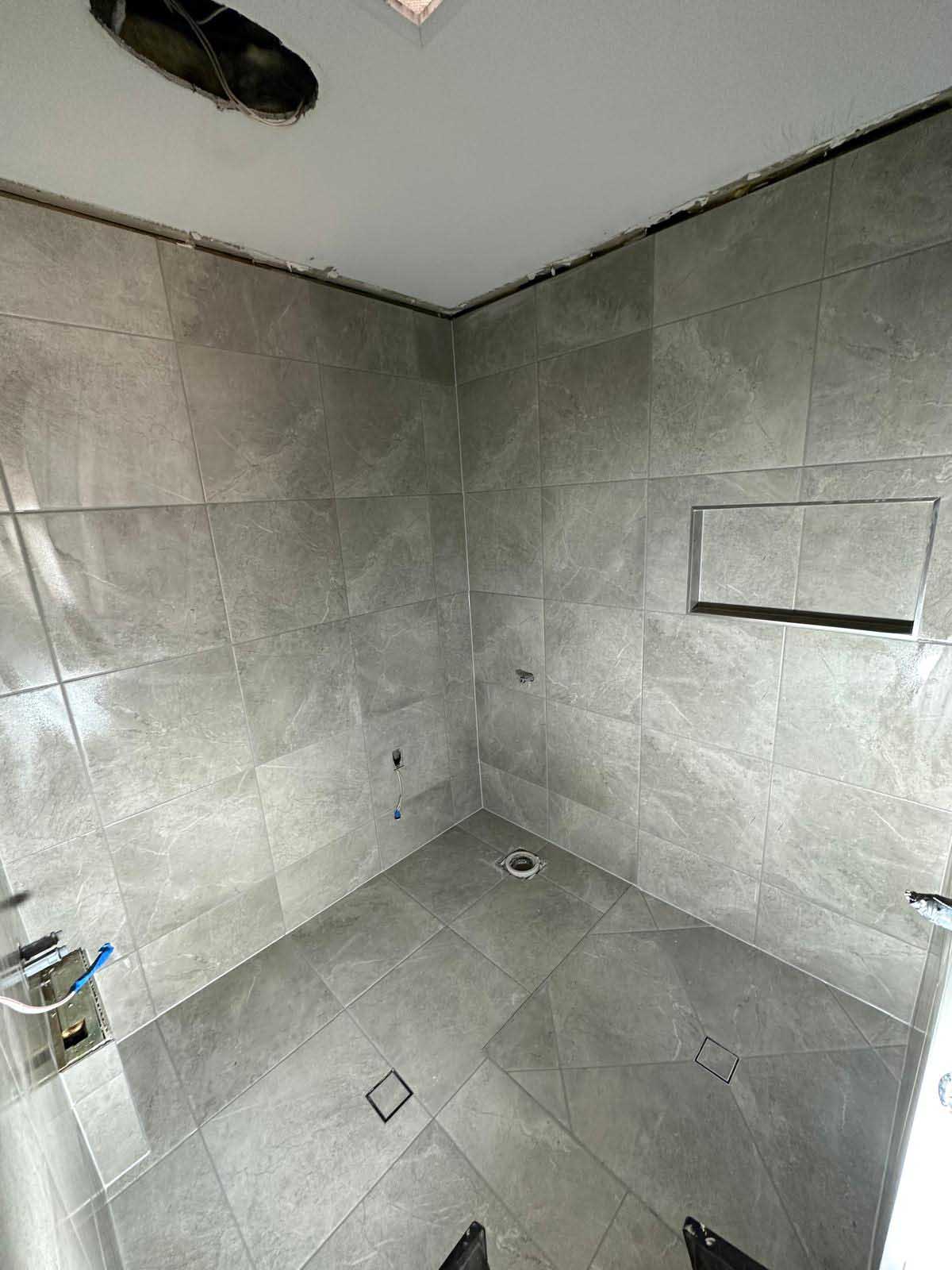 Shower with grey stone-look wall and floor tiles and a recessed niche