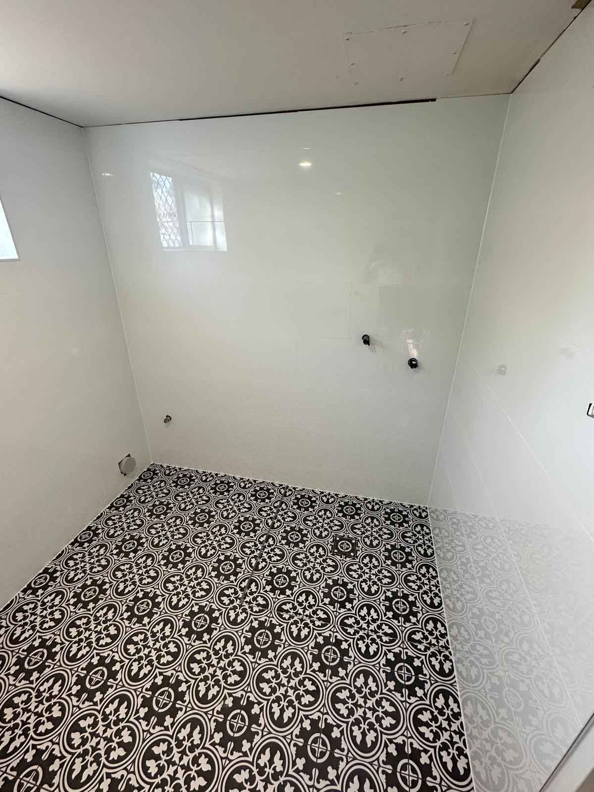 Black and white patterned bathroom floor tiles with plain white walls