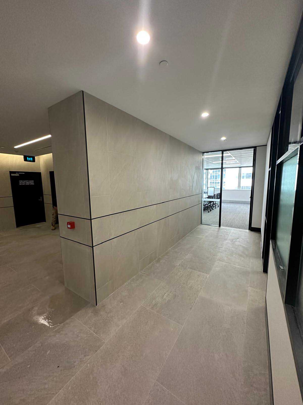 Office corridor with large-format grey floor and wall tiles and glass doors