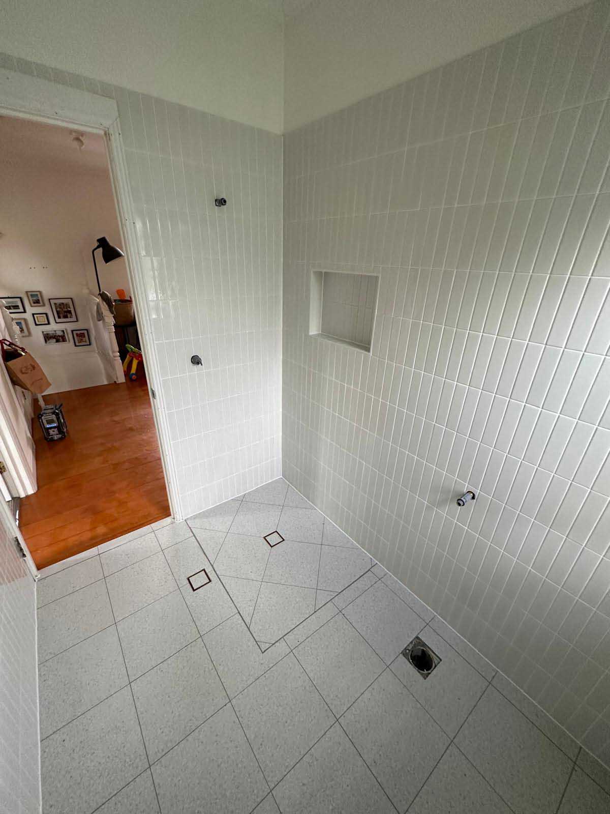 Shower with white vertical wall tiles, a recessed niche and white floor tiles