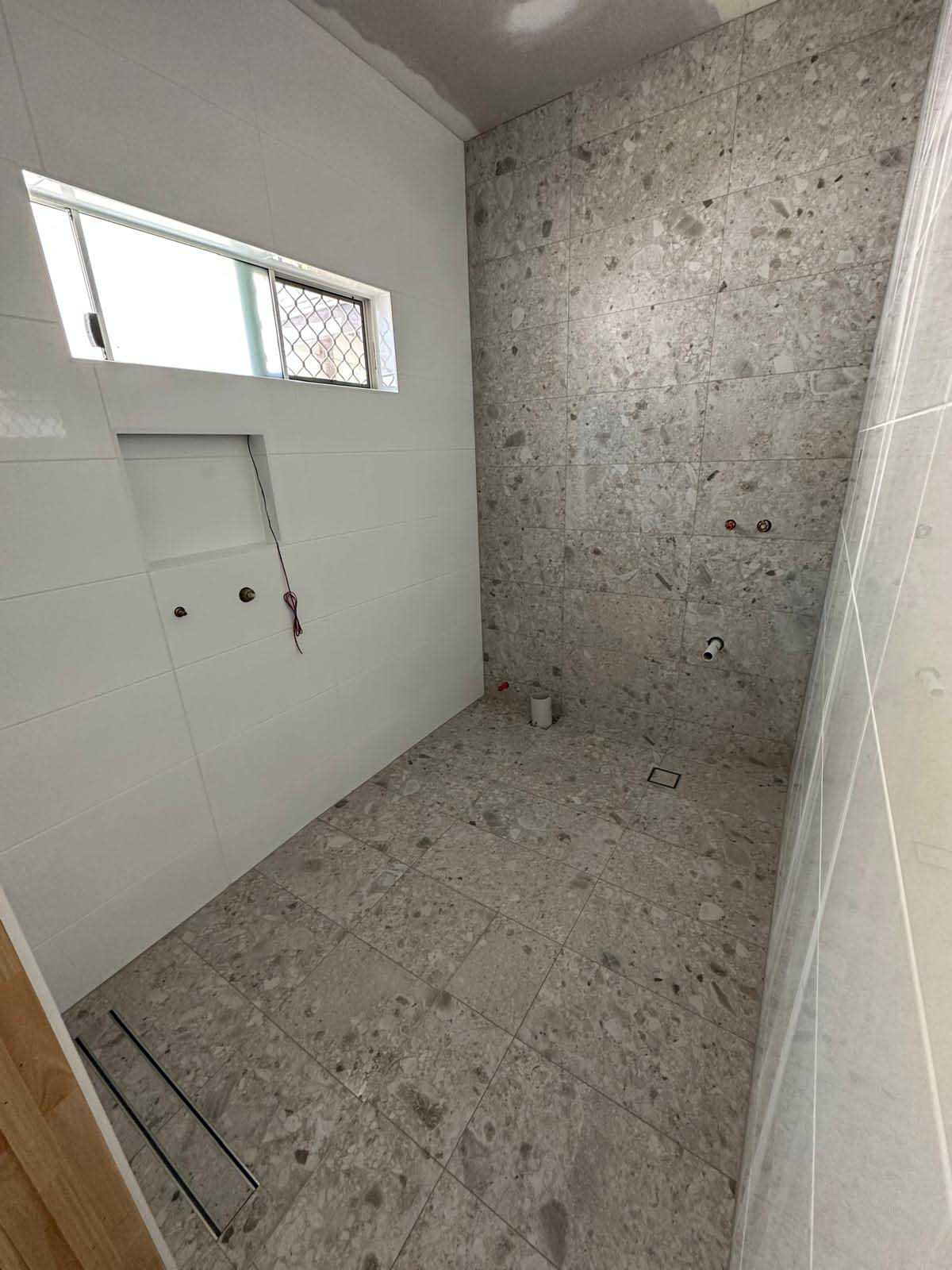 Bathroom with grey terrazzo-look floor and feature wall tiles and a linear drain