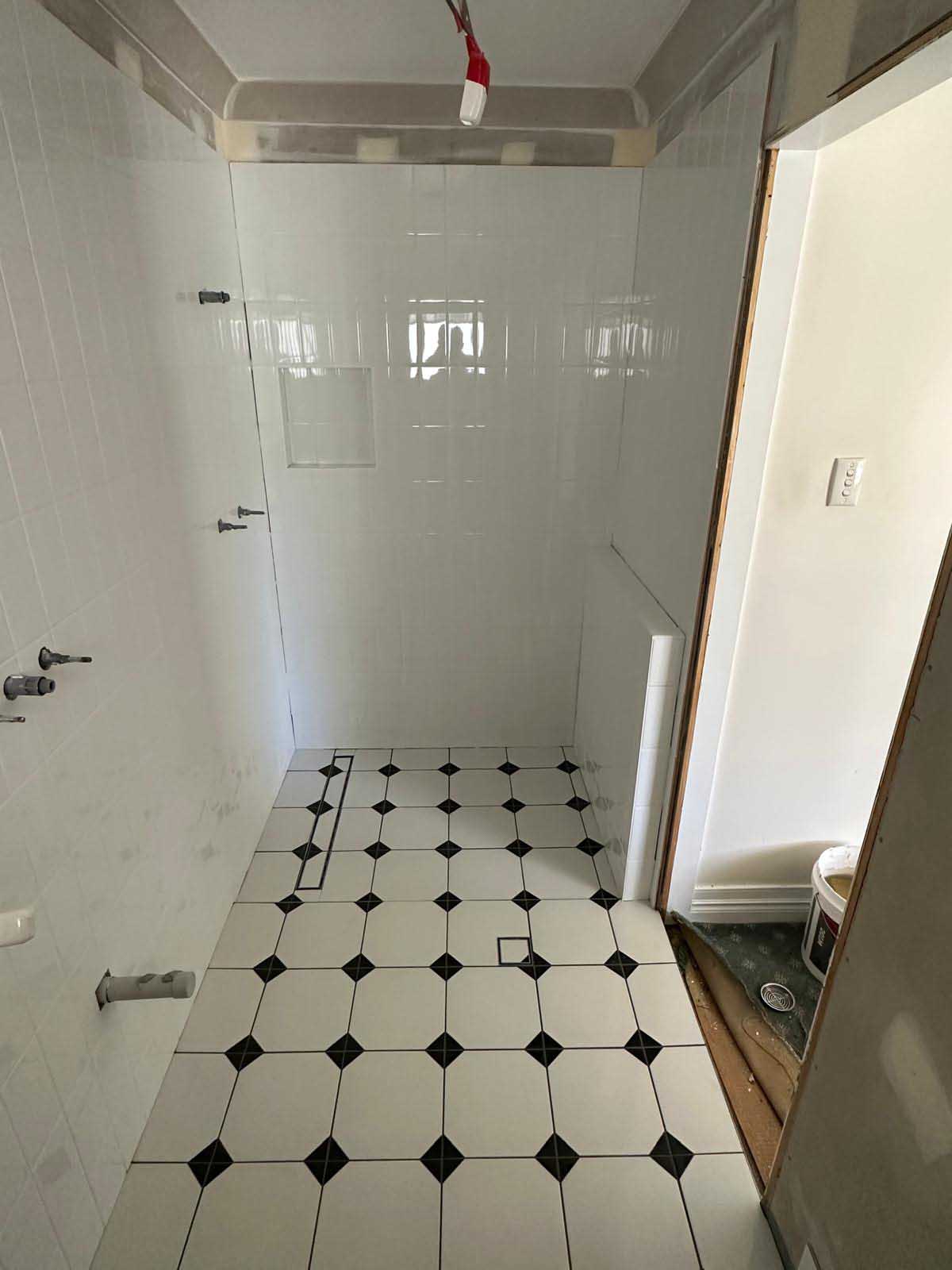 Bathroom floor in white octagon tiles with black dot inserts and white gloss walls
