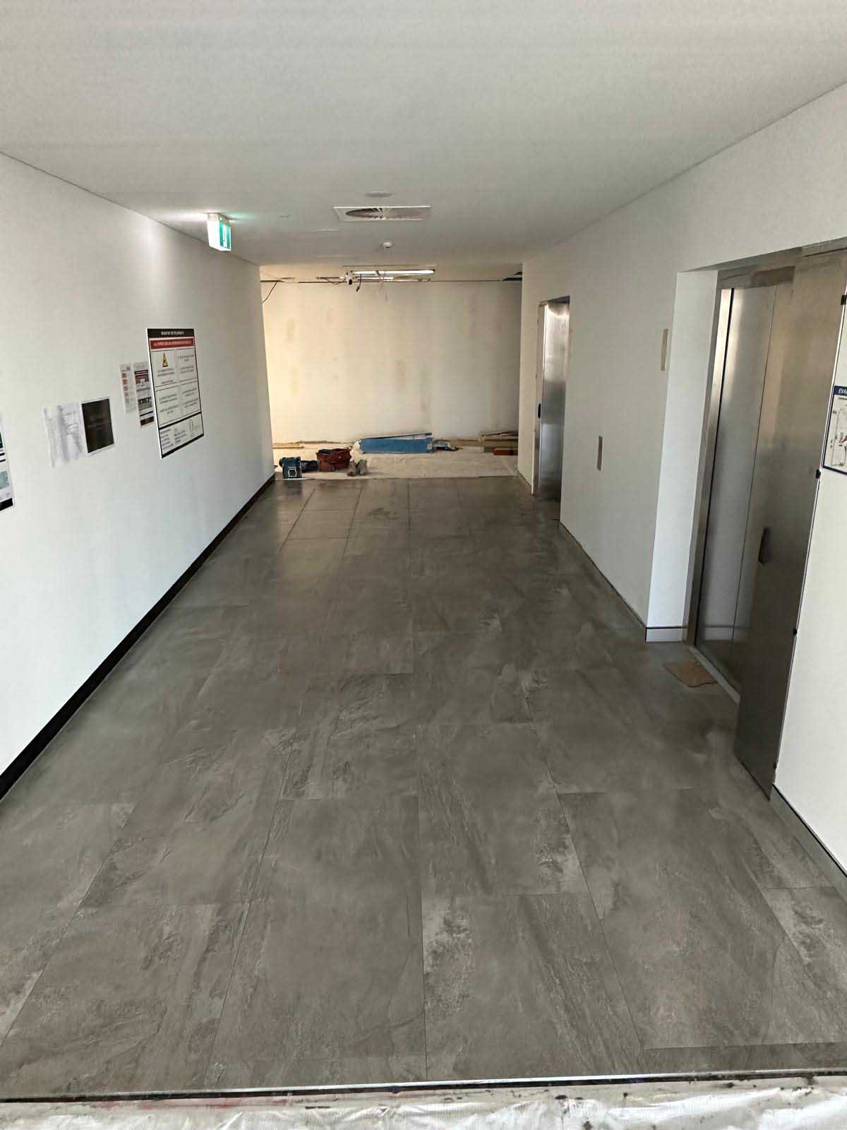 Long corridor with newly laid large-format grey floor tiles