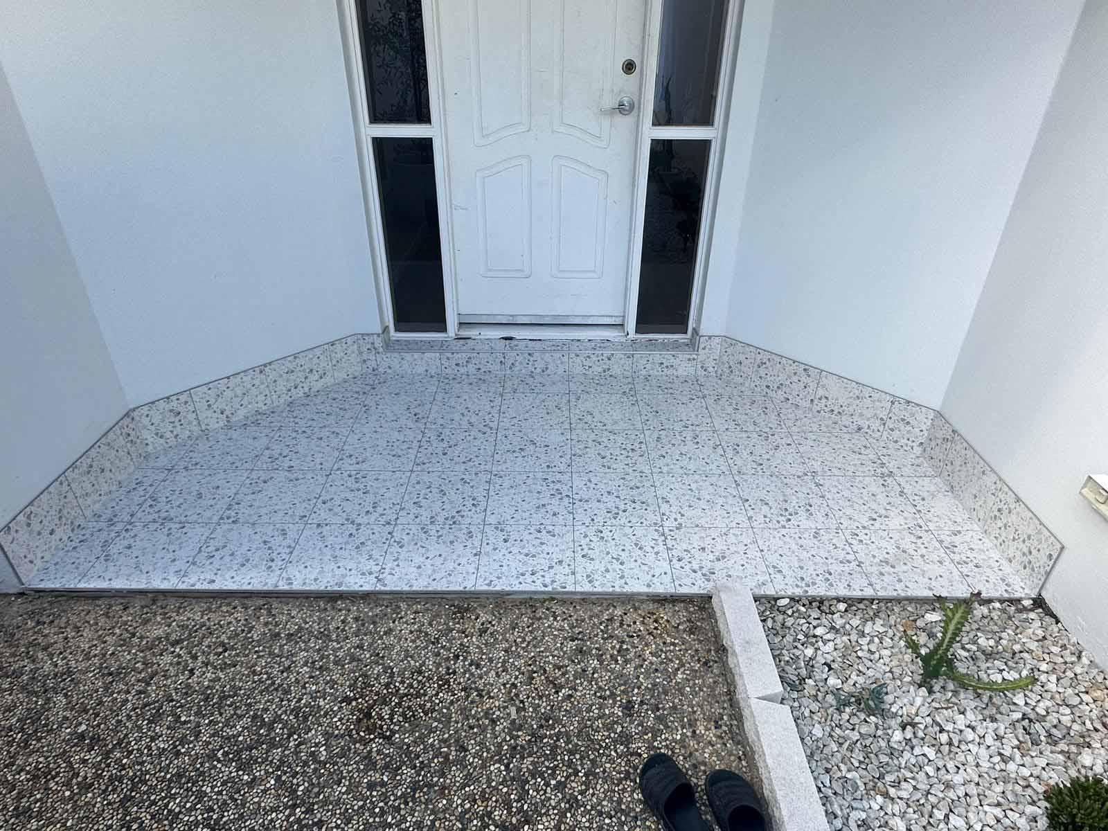 Front entry porch tiled in white speckled terrazzo-look tiles