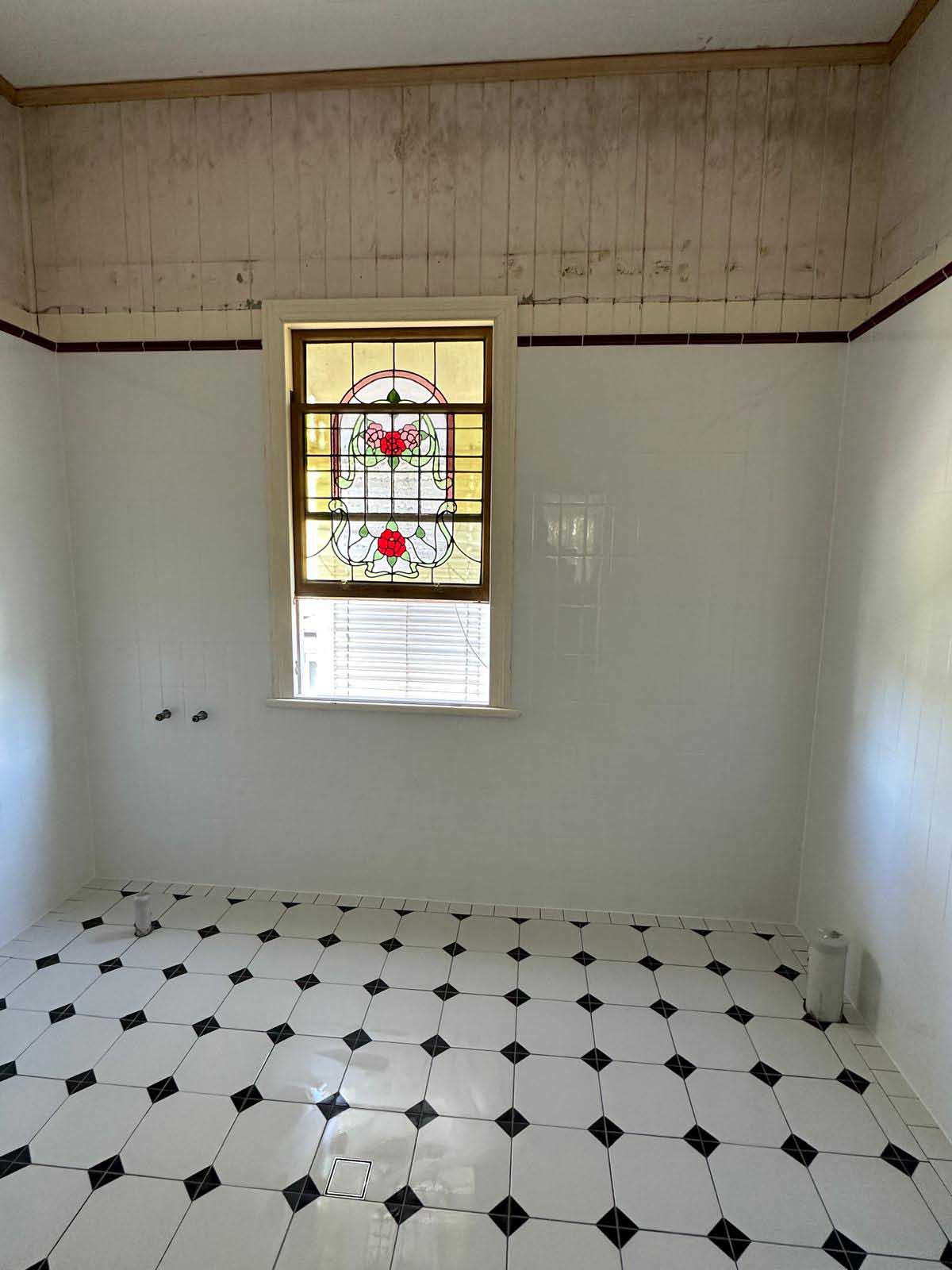 Bathroom with white octagon and black dot floor tiles beneath a leadlight window