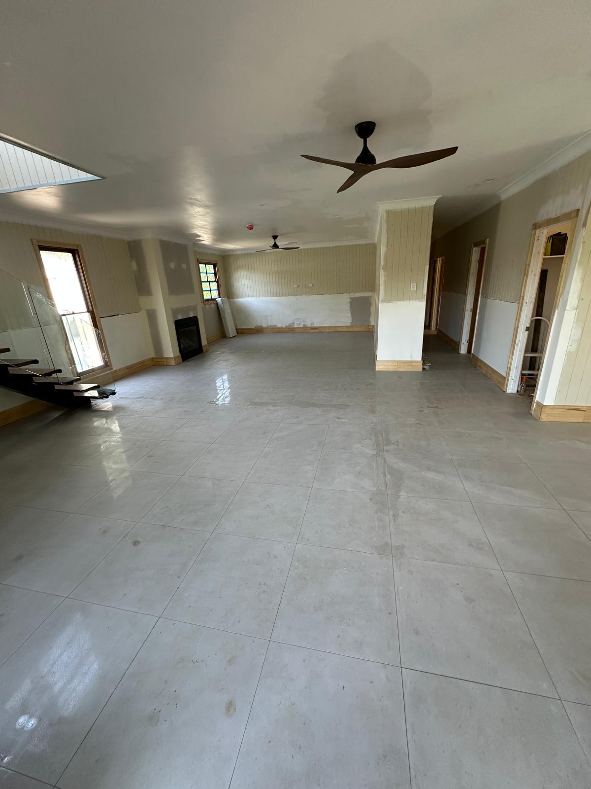 Open-plan living area with newly laid glossy grey floor tiles