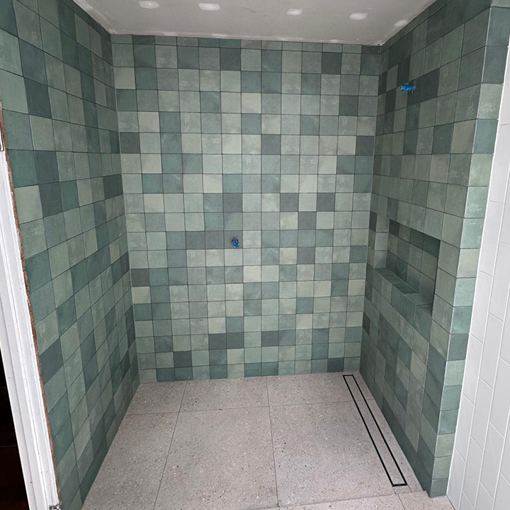 Shower with green-grey square wall tiles and a linear floor drain